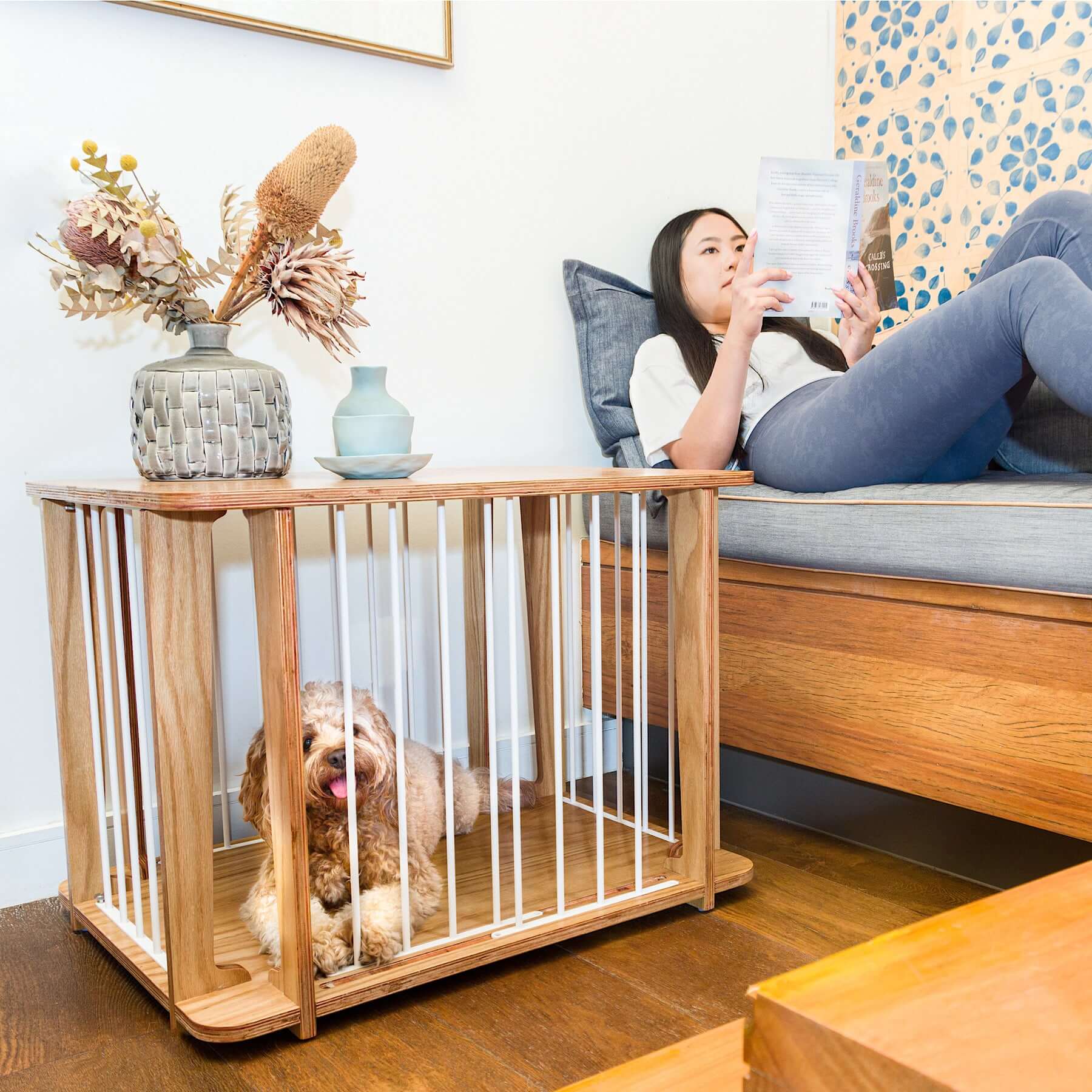 A woman enjoying reading beside Archie the Luxury Dog Crate with her pet inside