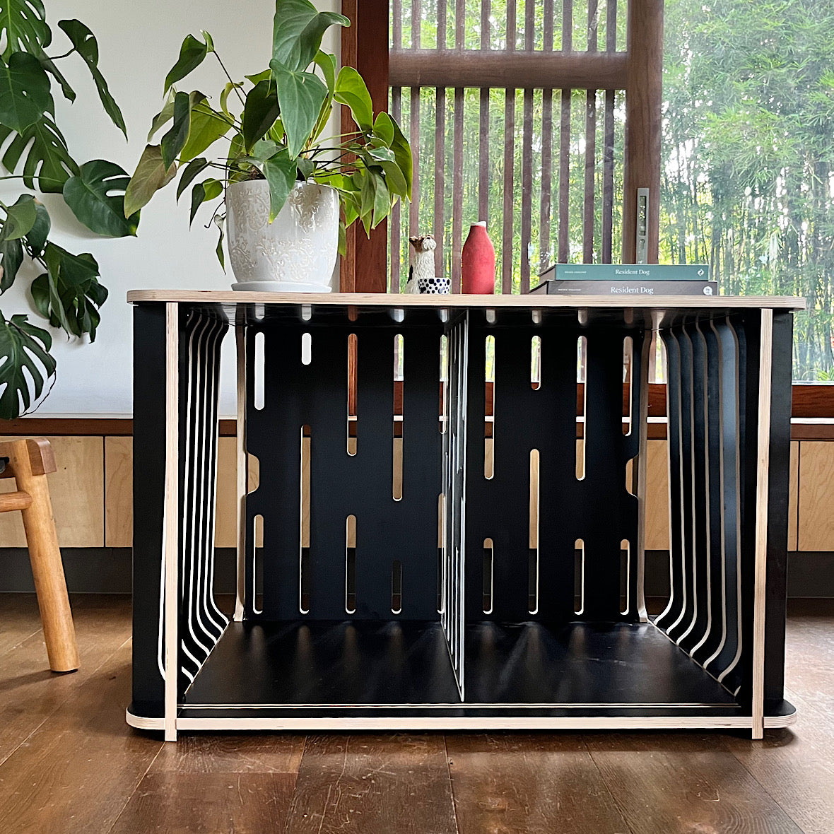 The Teddy Designer Dog Crate in black with divider, adorned with a houseplant